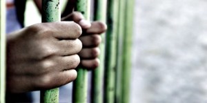 Child's hands holding prison bars