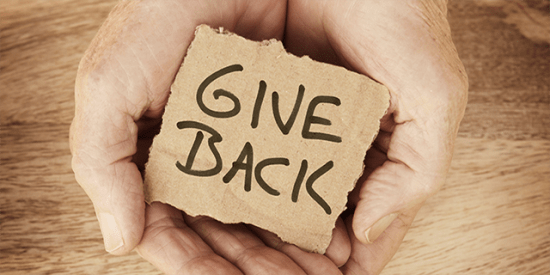Hands holding a sign saying "give back"