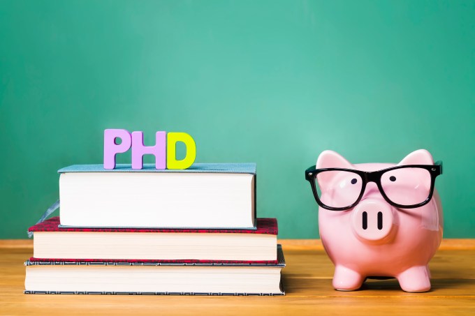 PhD degree theme with textbooks and piggy bank with glasses